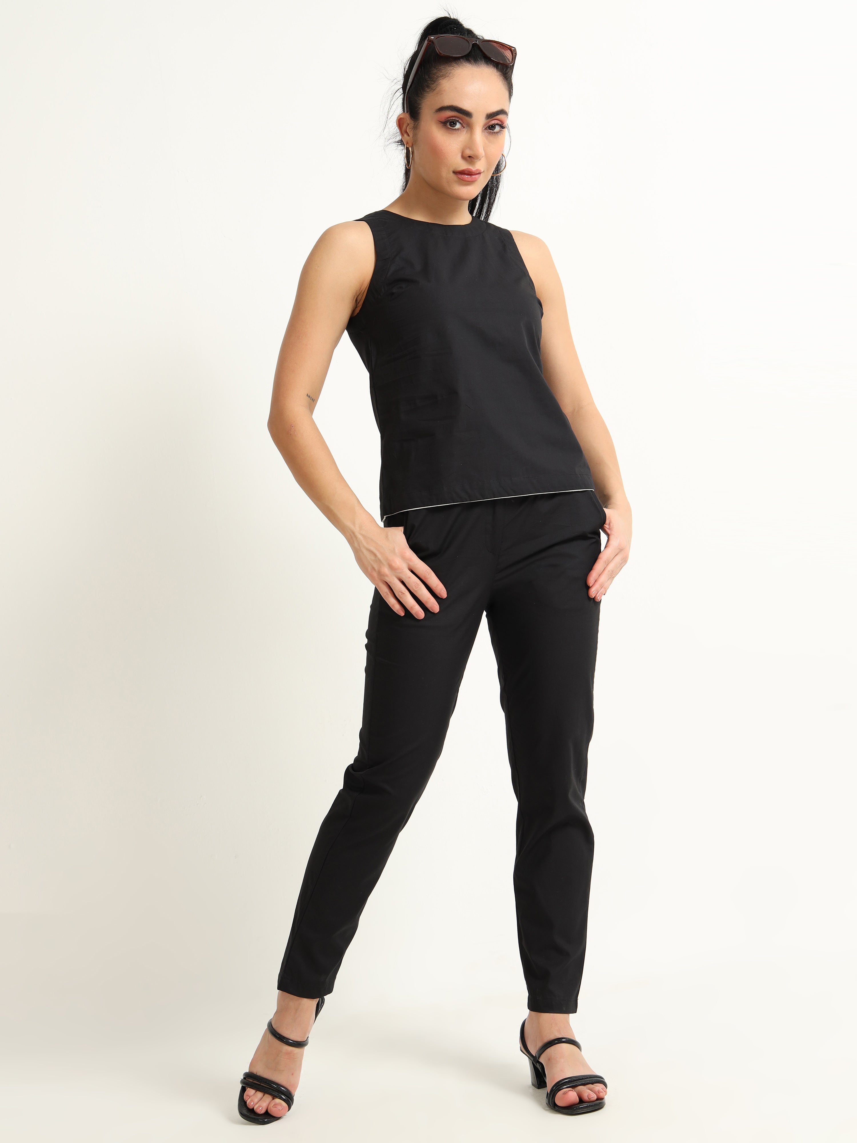 Organic Black Cotton Closed Neck Sleeveless Top With White Piping Detailing At The Hem Line.